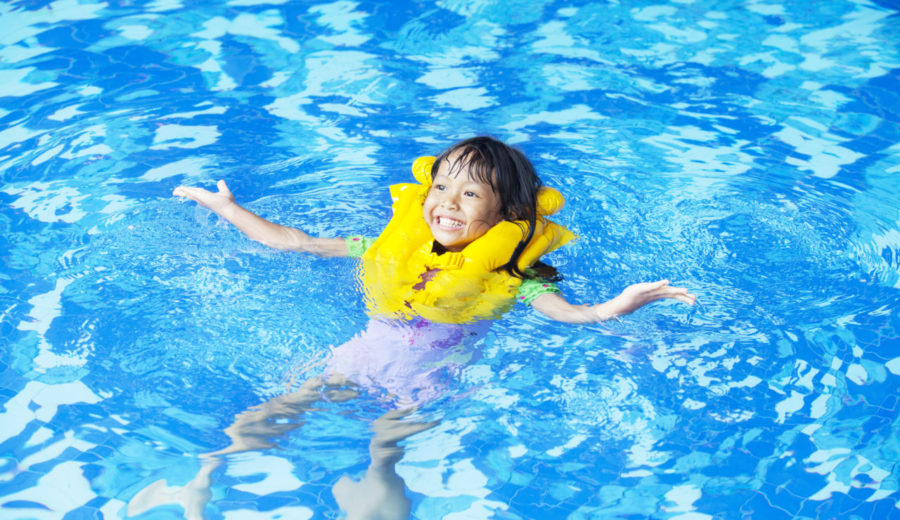 Toddler/Preschooler swimming in the pool with life jacket on for safety